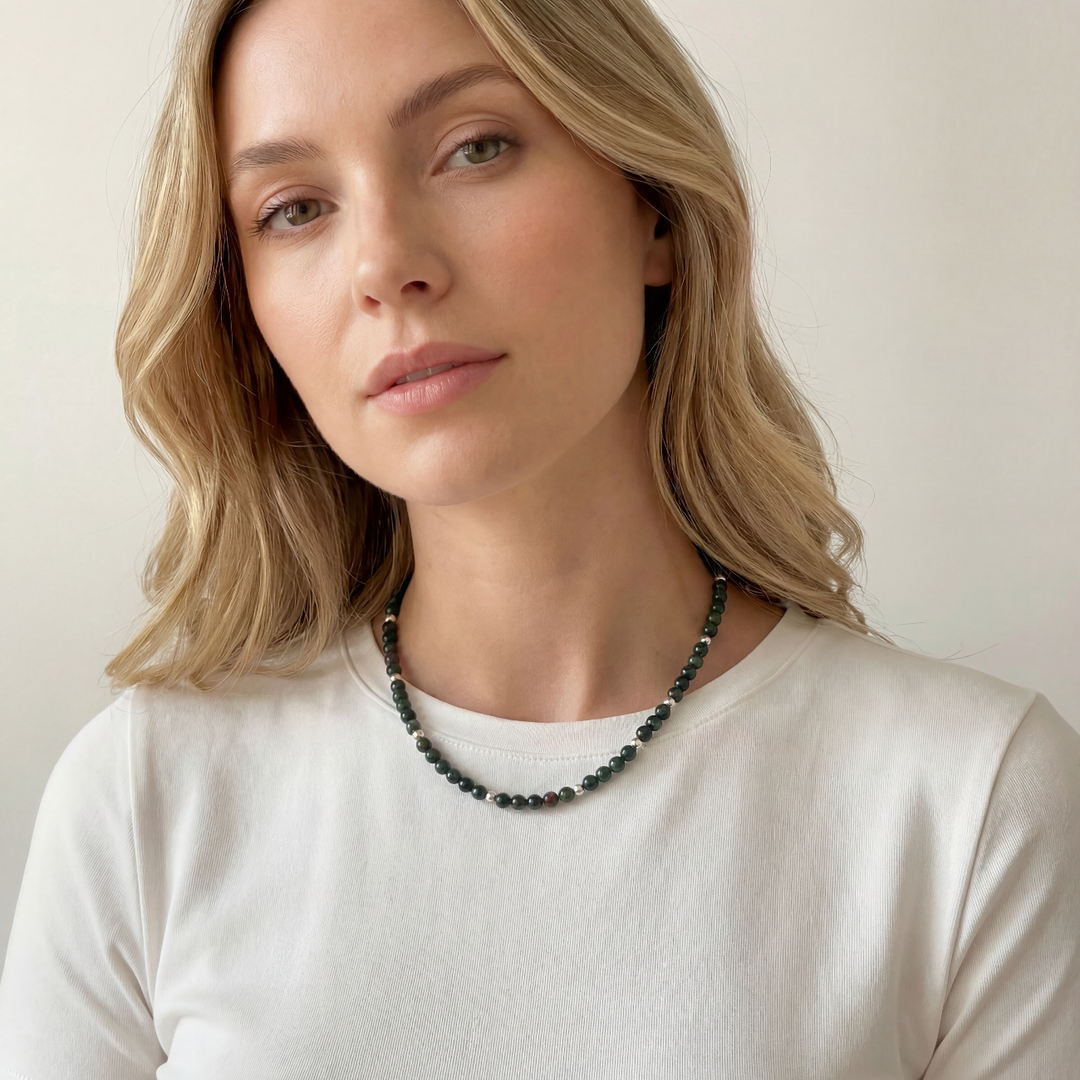Woman wearing a bloodstone gemstone necklace against a plain background