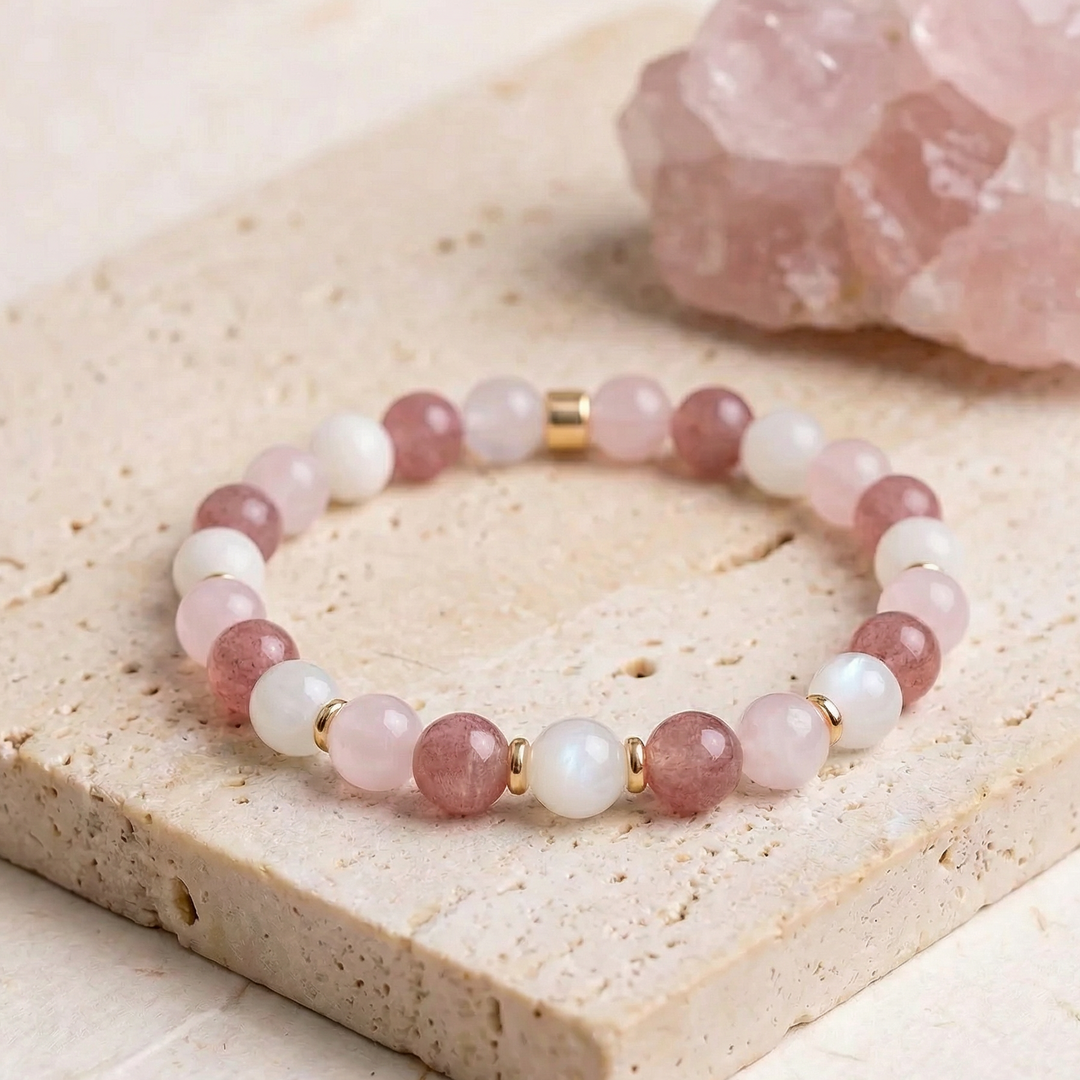 Beaded bracelet with pink and white stones on a stone surface with a crystal in the background