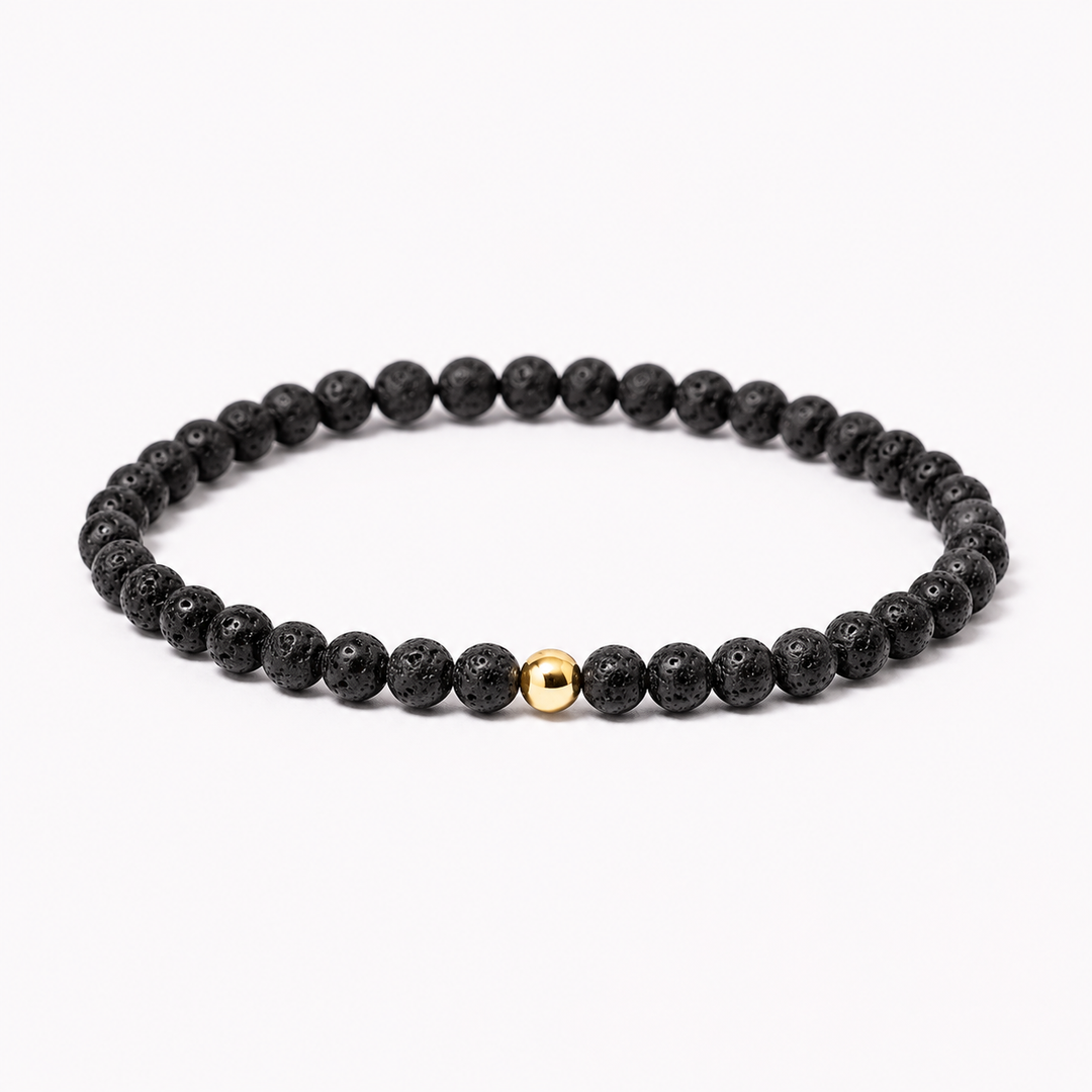 A beaded stretch bracelet made of textured black lava stone beads with a single polished gold accent bead, displayed on a clean white background.
