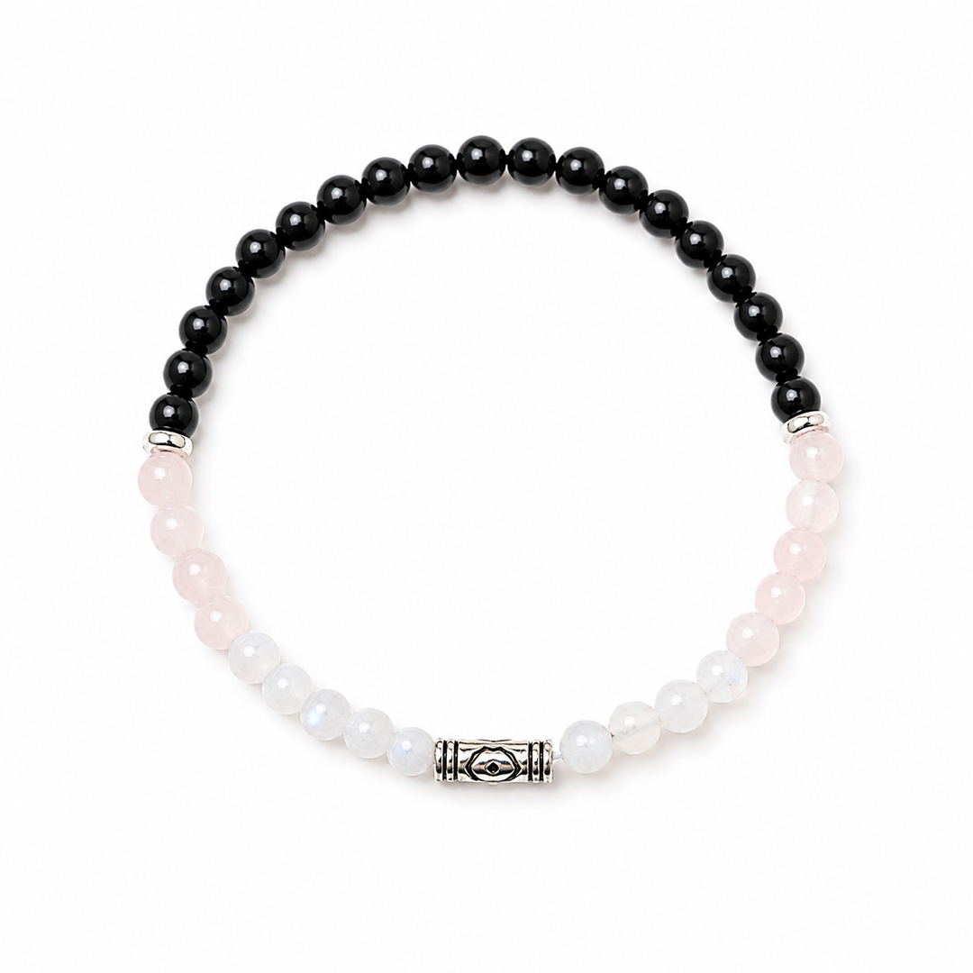 A beaded stretch bracelet featuring black onyx beads on one side and pale pink and milky white beads on the other, separated by silver-toned spacers and a central silver-toned decorative clasp, shown on a plain white background.