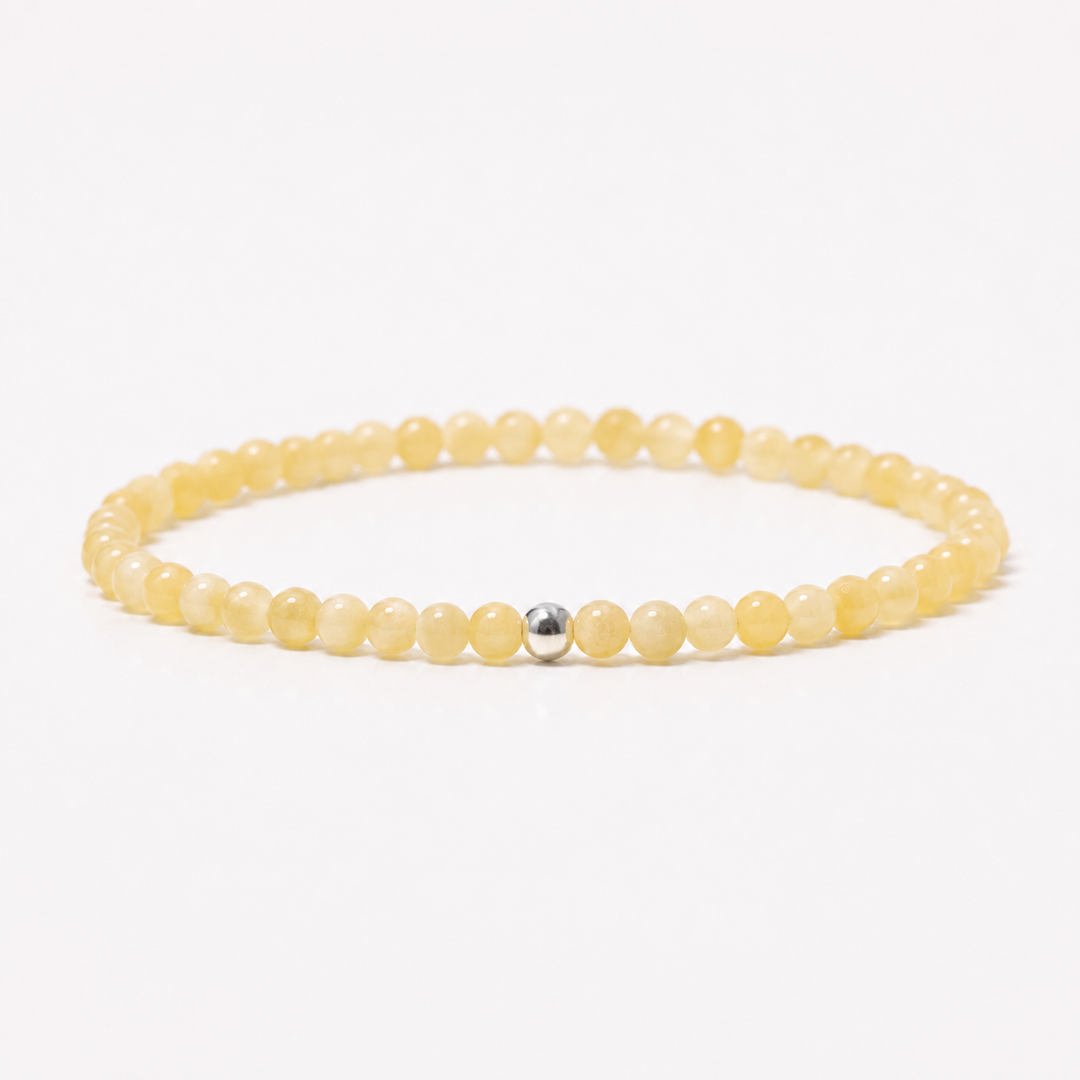 A beaded yellow calcite stretch bracelet made of small, round, pale yellow translucent beads with a single silver bead at the center, displayed on a clean white background.